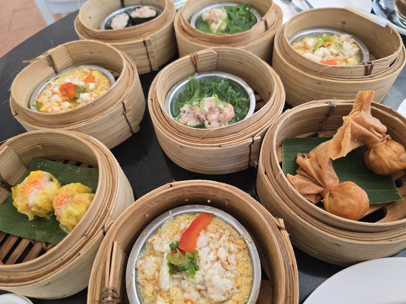 เข่งติ่มซำหลายเข่งบนโต๊ะ ทั้งขนมจีบ ถ้วยไข่ตุ๋นหน้าปู และเกี๊ยวทอด